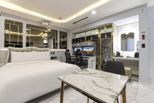 a bedroom with a white bed and a dining room at Hotel Felice Dongchon Amusement park in Daegu