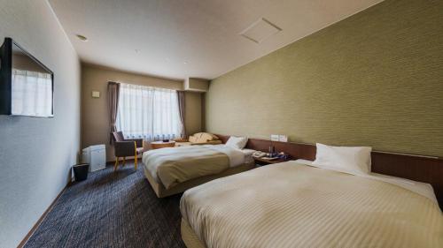 a hotel room with two beds and a desk at Onyado Toho in Aizuwakamatsu