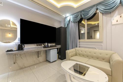 a living room with a couch and a flat screen tv at Hotel Felice Dongchon Amusement park in Daegu