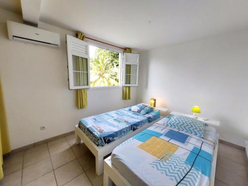 a bedroom with a bed and a window at La créola BAYALOCATION in Rivière-Pilote