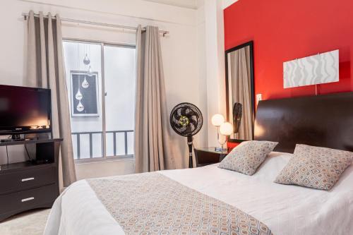 a bedroom with a large bed with a red wall at Hotel Victoria in Chinchiná