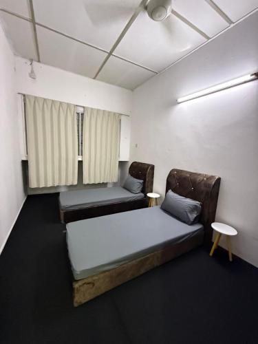 a small room with two beds and a window at Rina Hostel in Ipoh