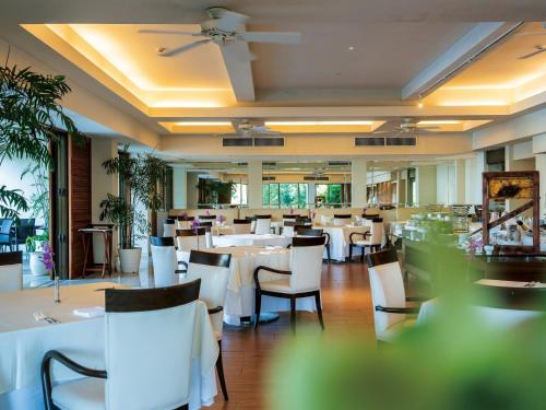 a dining room with white tables and chairs at The Atta Terrace Club Towers in Onna