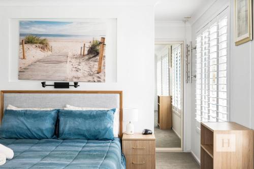 a bedroom with a bed with a picture of a beach at La Dolce Vita - Your next coastal getaway in Caves Beach