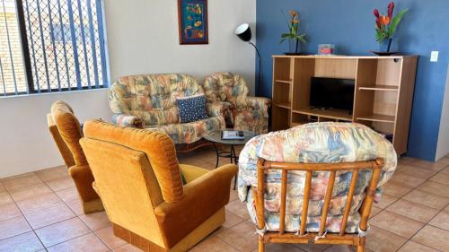 a living room with two chairs and a tv at Fantastic Views From Top Floor in Bongaree