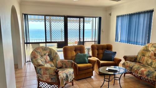 a living room with chairs and a couch and a table at Fantastic Views From Top Floor in Bongaree