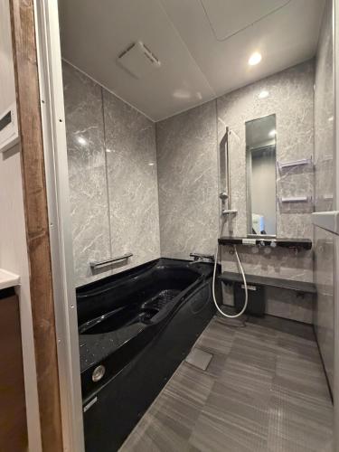 a bathroom with a black tub and a mirror at OZ Fuji in Fujiyoshida