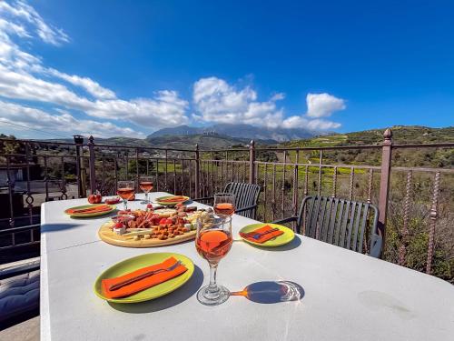a table with plates of food and glasses of wine at Muses Mountain View in Ayía Varvára