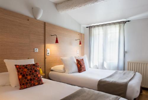 a hotel room with two beds and a window at Hôtel Edmond Rostand in Marseille