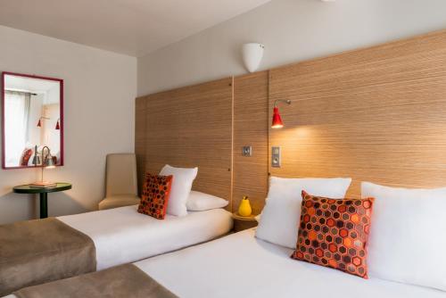 a hotel room with two beds and a mirror at Hôtel Edmond Rostand in Marseille