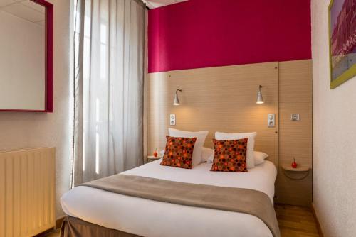 a bedroom with a large bed with a red wall at Hôtel Edmond Rostand in Marseille