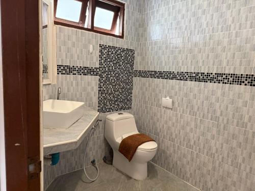 a bathroom with a white toilet and a sink at Serene Resort Pattaya in Nong Prue