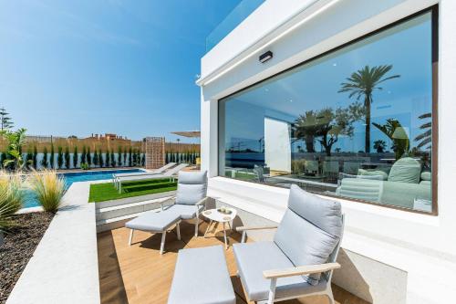 a patio with three chairs and a table and a pool at Edelweiss in Los Alcázares