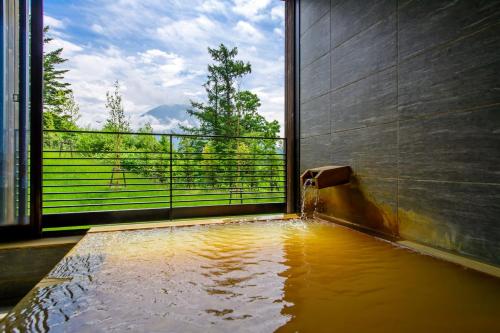 a bath tub with water in it with a window at NISEKO Inn of Youtei Raku Suisan in Kutchan
