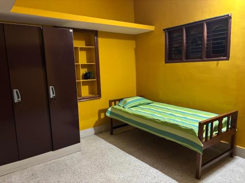 a small room with a bed and a yellow wall at Untitled Space Residency in Bangalore