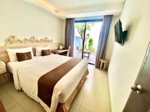 a hotel room with a large bed and a window at Horison Kuta Bali in Kuta