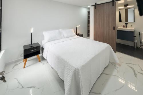 a white bedroom with a white bed and a bathroom at Galería 305 in Cartago