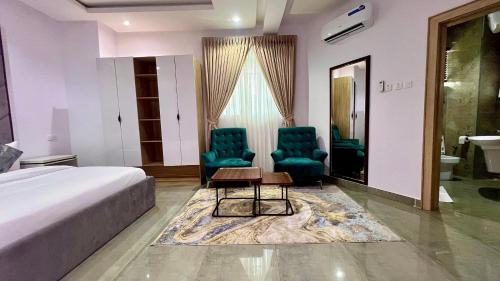 a hotel room with two chairs and a bed at Hillgates Apartments Ikeja in Ikeja