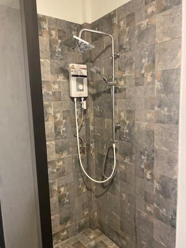 a shower in a bathroom with a stone wall at Isaan Country Retreat in Mukdahan