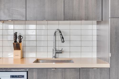 a kitchen with a sink and white tiles at Eleve Toronto Residences in Toronto