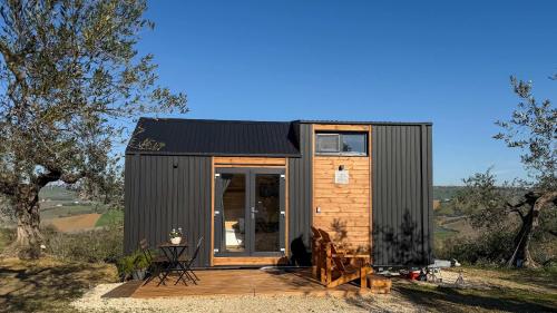 a tiny house with a black roof and a wooden deck at Intermezzo X by Tiny Away in Citta' Sant'Angelo