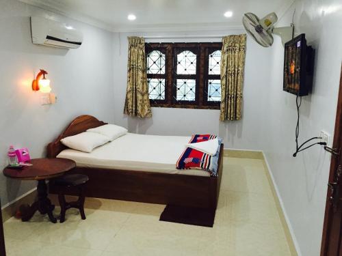 Schlafzimmer mit einem Bett, einem Tisch und einem Fenster in der Unterkunft The Blue Guest House in Battambang