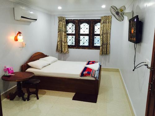 1 dormitorio con cama, mesa y ventana en The Blue Guest House en Battambang