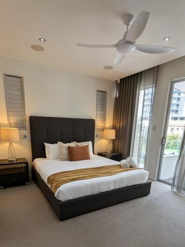 a bedroom with a large bed with a ceiling fan at Luxury House steps from Mooloolaba Beach in Mooloolaba