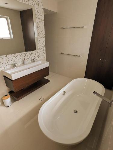 a white bathroom with a tub and a sink at Luxury House steps from Mooloolaba Beach in Mooloolaba