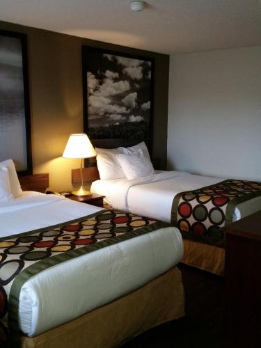 a hotel room with two beds and a lamp at Super 8 by Wyndham Brockville in Brockville