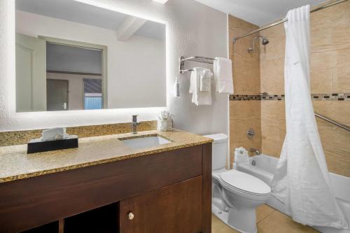 a bathroom with a sink and a toilet and a mirror at Days Inn by Wyndham Florida City in Florida City