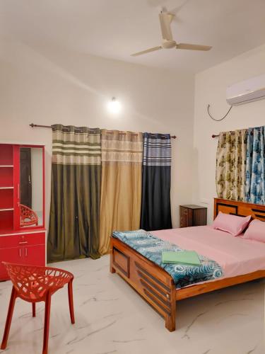 a bedroom with a bed and a chair and curtains at Star Varkala Homestay in Varkala