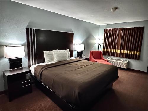 a hotel room with a bed and a red chair at Owensville Inn in Owensville
