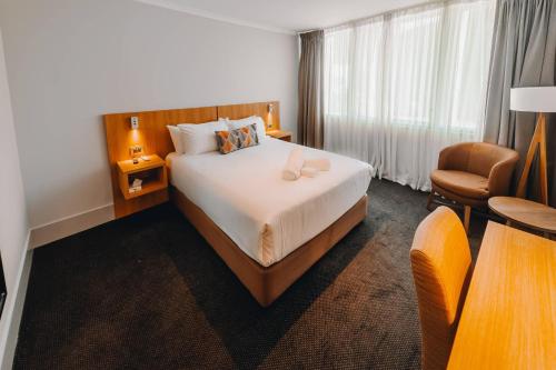 a hotel room with a bed and a chair at Clarion Hotel Townsville in Townsville