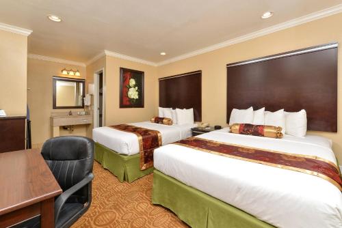 a hotel room with two beds and a desk at Rodeway Inn San Diego Near SDSU in San Diego