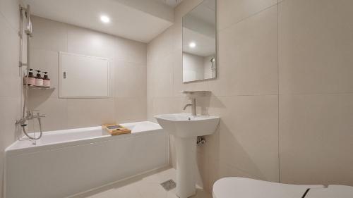 a white bathroom with a sink and a bath tub at Maison de Centum Busan in Busan