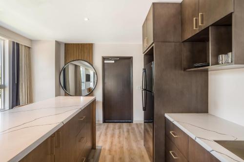 a kitchen with wooden cabinets and a mirror at Cambria Hotel Templeton - Paso Robles in Templeton