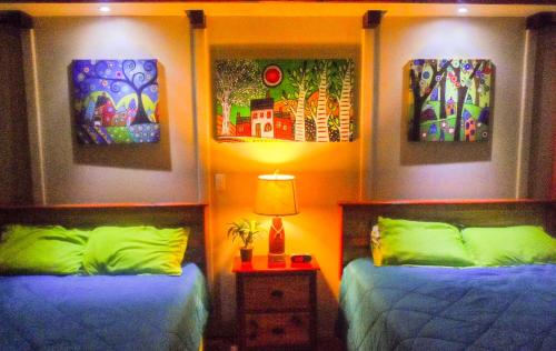 a bedroom with two beds and paintings on the wall at Family Guest House in Quebradillas