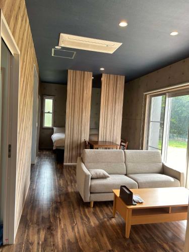 a living room with a couch and a bedroom at リベルテ Work & Vacation Villa Nosoko in Ibaruma