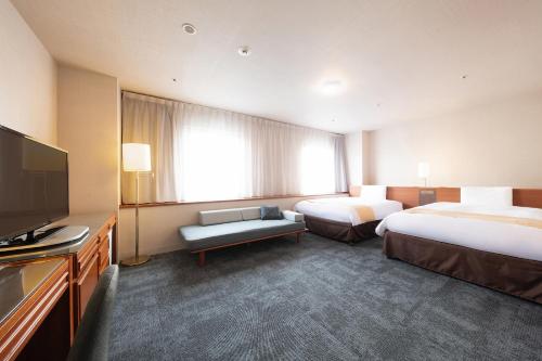 a hotel room with two beds and a flat screen tv at Vessel Inn Yachiyo Katsudai Station in Yachiyo