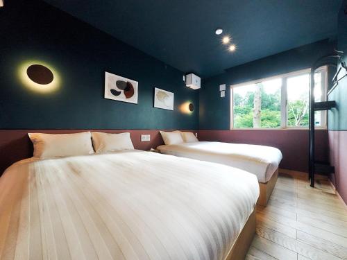 two beds in a room with blue walls and a window at Rakuten STAY VILLA Hakone Sengokuhara South Wing 104 or 105 BBQ Terrace Pet allowed Capacity of 10 persons in Hakone