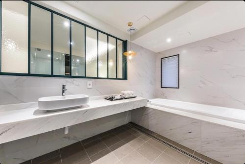 a white bathroom with a sink and a tub at STYLE Hotel in Seoul