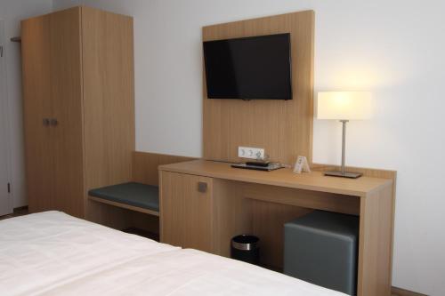 a hotel room with a bed and a desk with a television at Hotel Seepark Garni in Überlingen