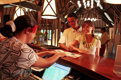 a woman sitting at a bar in front of a computer at Sofitel Kia Ora Moorea Beach Resort in Maharepa