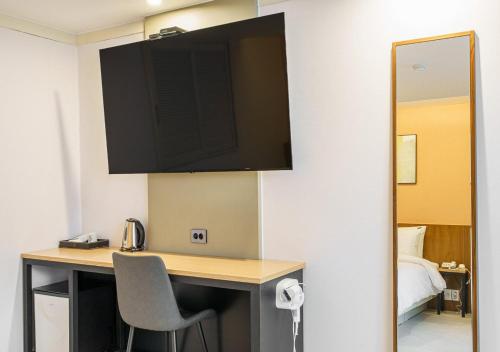 a room with a desk with a television on the wall at Ilsan Hotel K in Goyang