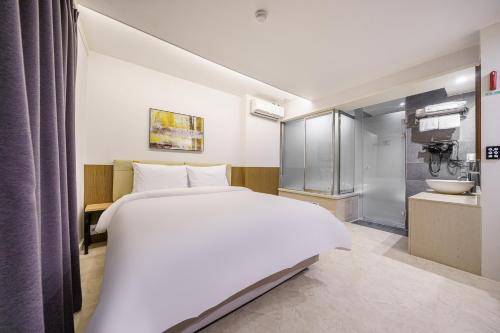 a bedroom with a large white bed and a bathroom at Ilsan Hotel K in Goyang