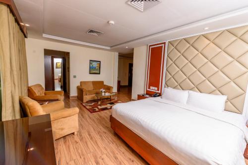 a bedroom with a large bed and a living room at Hotel One Faisalabad in Faisalabad