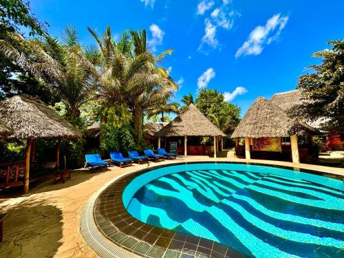 a swimming pool at a resort with chairs and palm trees at Stay Social Diani - Backpackers & Social Hub in Diani Beach