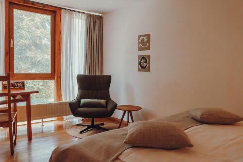 a bedroom with a bed and a chair and a window at Hotel Gut Hühnerhof in Gründau