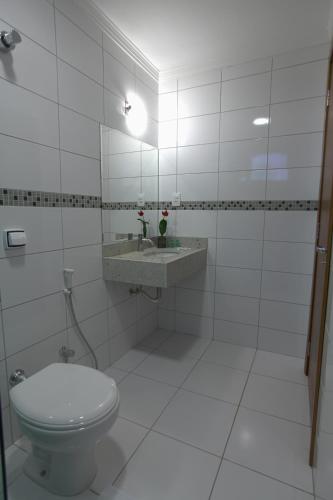 a white bathroom with a toilet and a sink at Skala Traveling Hotel in Cuiabá